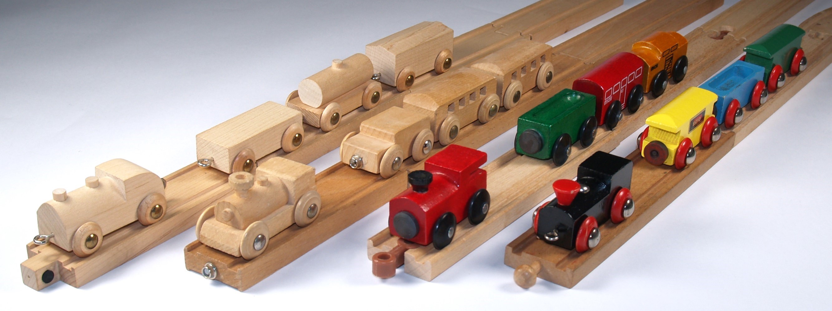 Fig. 2 - Photo comparing early vintage train sets from left to right, Skaneateles, Jack Built, Micki Leksaker and BRIO.  Note the variety of train & track connectors, but each train can still operate on any competitor’s track.